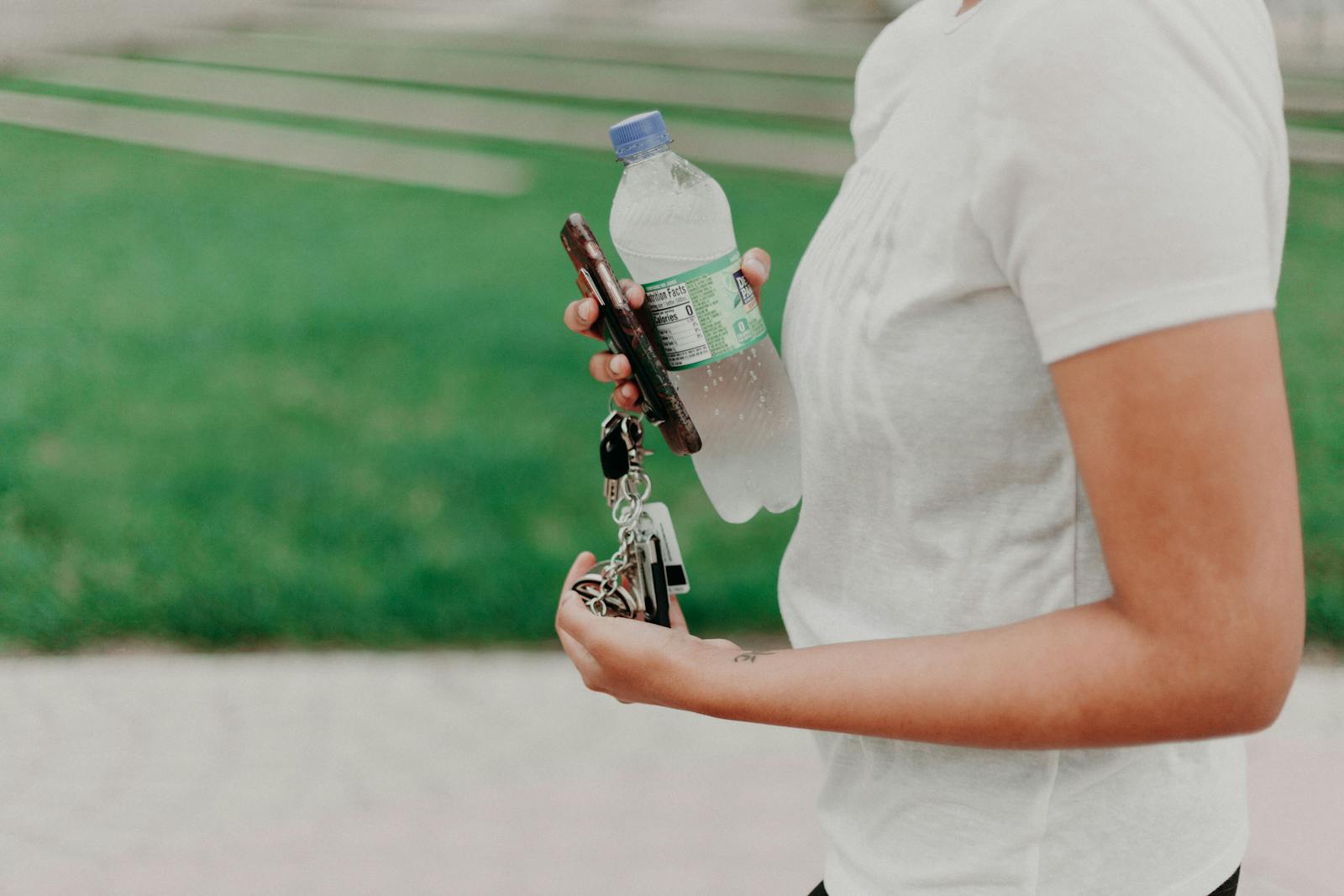 A hand holding a water bottle 