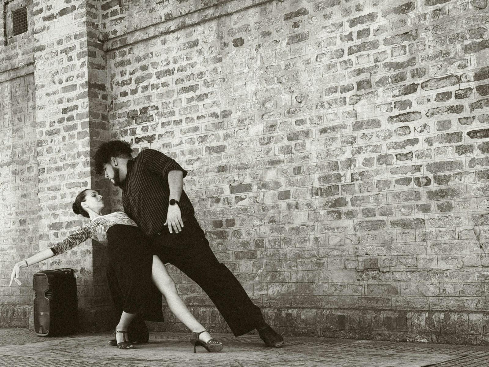 A man and a woman leaning against a brick wall