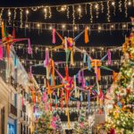 Vibrant Christmas decorations with piñatas and lights in the festive streets of Oaxaca at night.