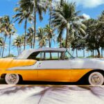 A yellow and gray car parked in front of palm trees