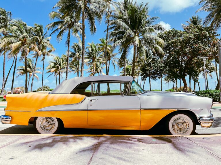 A yellow and gray car parked in front of palm trees